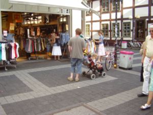 Porth , 2006 © Situation im Alltag!?! - Er denkt hinterm Kinderwagen: "Wie lange dauert's noch?" Das Kind im Kinderwagen überlegt: "Oh, ist das langweilig." Sie meint im Laden: "Immer diese Hetze beim Einkaufen."